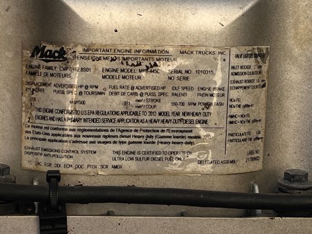 Mack Trucks engine information plate with various specifications and VIN-like text, mounted on a truck engine bay area.