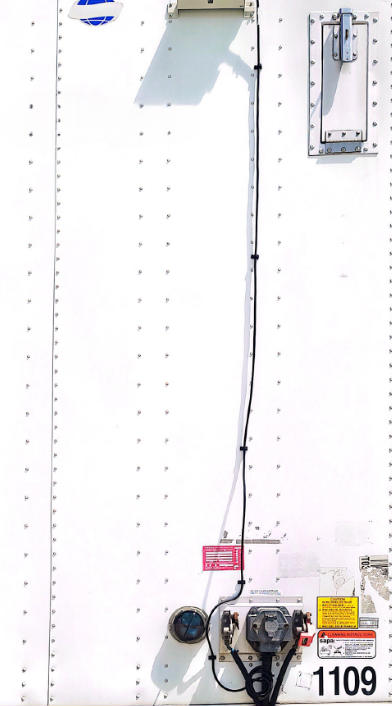 Trailer rear interior showing electrical control device and label stickers near lower right corner.