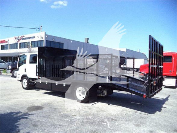 Isuzu NPR-HD flatbed tow truck with a hydraulic tilt-bed and side rails, white cab, black metal ramp bed, parked in lot.