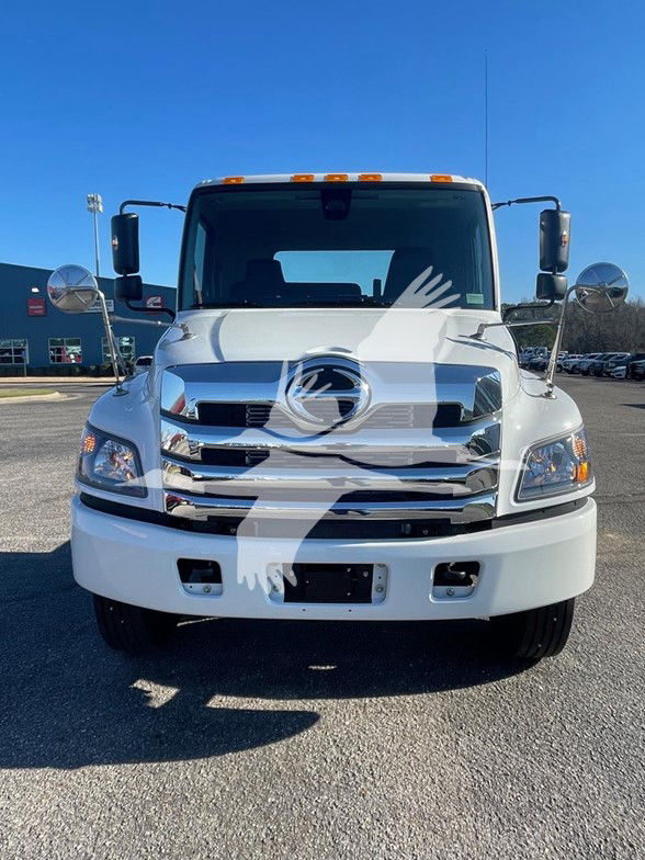 Front view of a white 2025 Hino L6 cab and chassis truck showing chrome grille, bumper, and side mirrors.