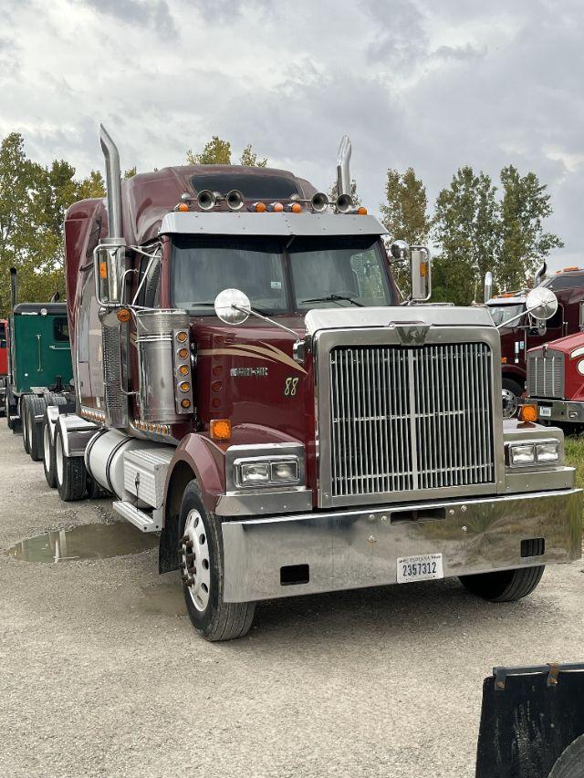 Truck front view showing maroon Western Star with chrome grille, dual air intakes, large silver bumper, and Detroit 14L badge.