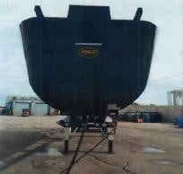 Frontal view of a 2023 steel-framed frameless half-round dump trailer showing the underside and support legs.