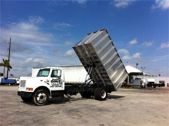 Dump body truck with raised metal bed on a white cab chassis, Advanced Fabricators 16 ft dump body, stock number 16CH72A, in a parking lot.