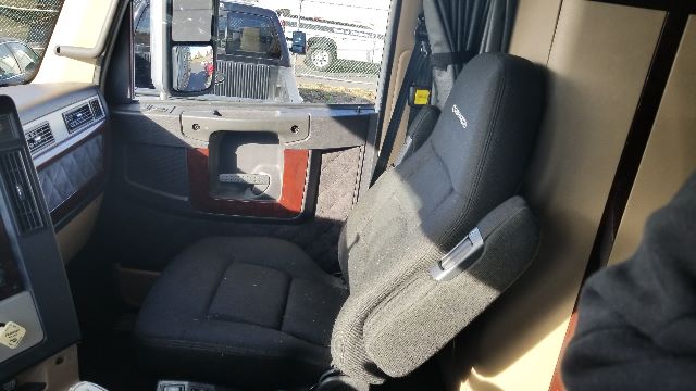 Truck cab interior showing driver's seat and door panel of a Freightliner Coronado 132. No visible labels of fluids or parts in this view.