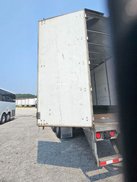 Utility trailer with open cargo area showing side and back panels, white exterior, rear lights visible.