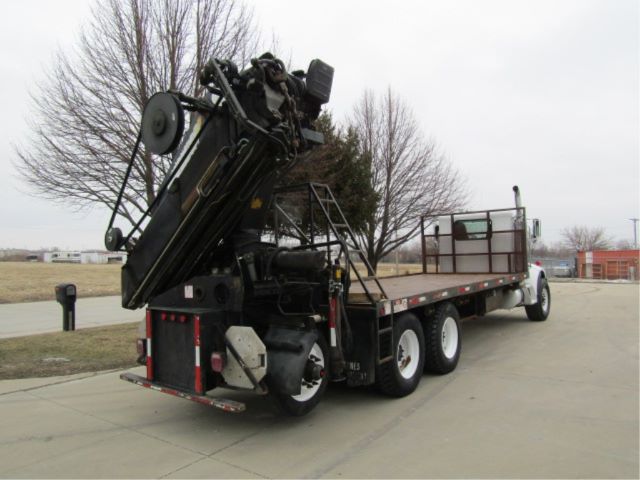 Peterbilt 330 boom truck with flatbed trailer seen from rear-left, crane folded on bed.
