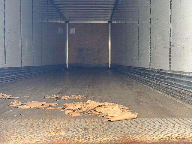 Interior of a 2009 Stoughton dry van trailer showing empty cargo area with wood debris on the floor and metal diamond plate at the ramp edge.