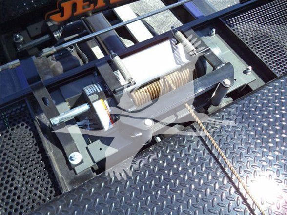 Ram 5500 tow truck winch mechanism mounted on diamond plate toolbox; visible wire rope and winch drum with springs and mounting brackets.