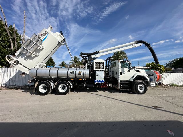2013 International 7500 vacuum truck with long vacuum hose and rear silo, side view showing tank and boom arm.