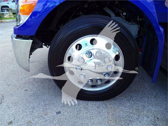 Front wheel of a blue Peterbilt truck showing polished chrome hubcap and black tire.
