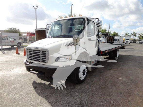 Flatbed tow truck showing Freightliner M2 106 cab with white exterior and extended flatbed.