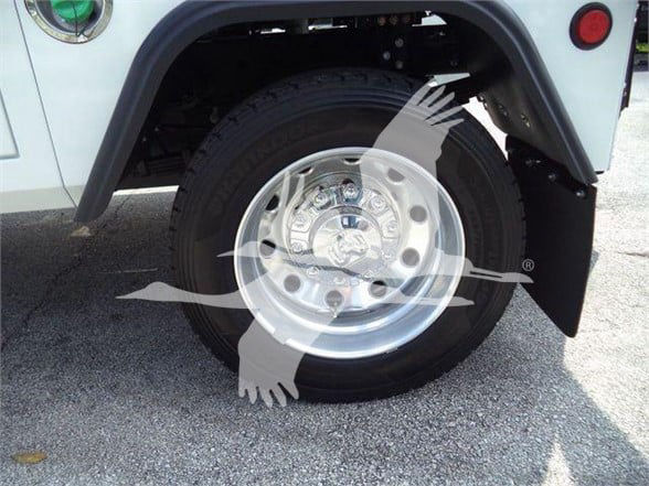 Wheel and fender of a white Ram 5500 truck showing a chrome hubcap/steel wheel, black tire, and partial fender. faint circular watermark overlay.
