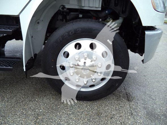 Truck wheel and front fender showing front wheel with chrome hub and tire, part of a Freightliner M2 106 truck.