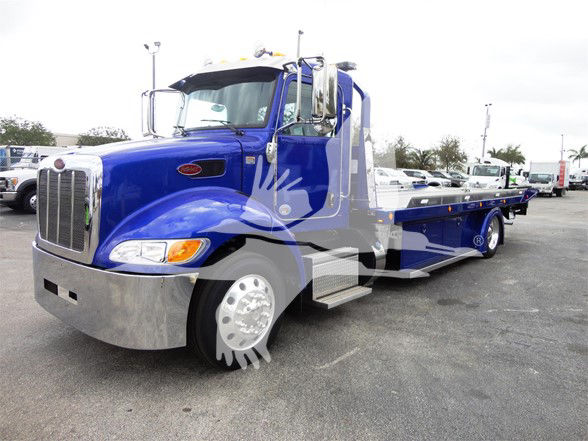Blue 2022 Peterbilt 337 tow truck in a lot, long wheelbase, with flatbed bed and chrome front bumper.