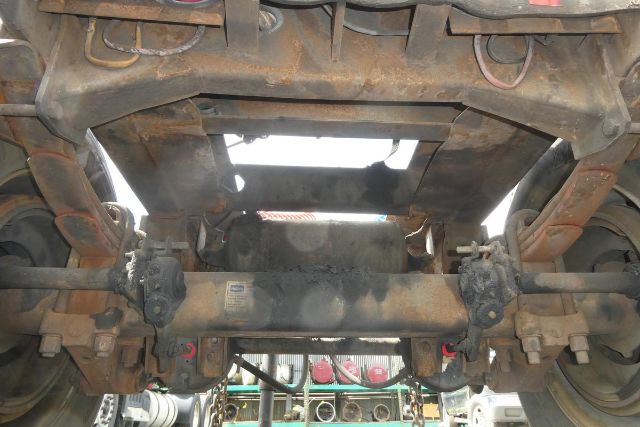 Undercarriage view of a Fruehauf ELFI trailer showing stamped steel frame, axles, leaf springs, and universal joints. Visible components include suspension and drive-related hardware.