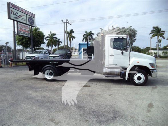 2017 Hino 258LP hooklift truck in side view with flatbed and gray cab on a dealership lot.