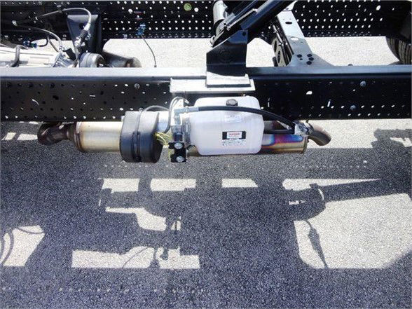 Isuzu NPR HD truck chassis showing a fuel or exhaust aftertreatment canister mounted under the frame.