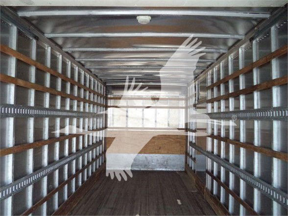 Truck trailer interior with metal side rails and wooden floor, empty cargo space. Overlaid watermark of a hand graphic.