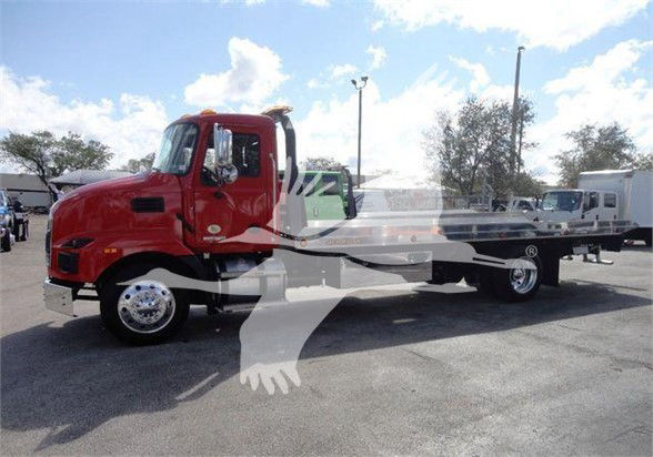 Mack MD6 tow truck side view showing red cab and long flatbed with dual rear axles.