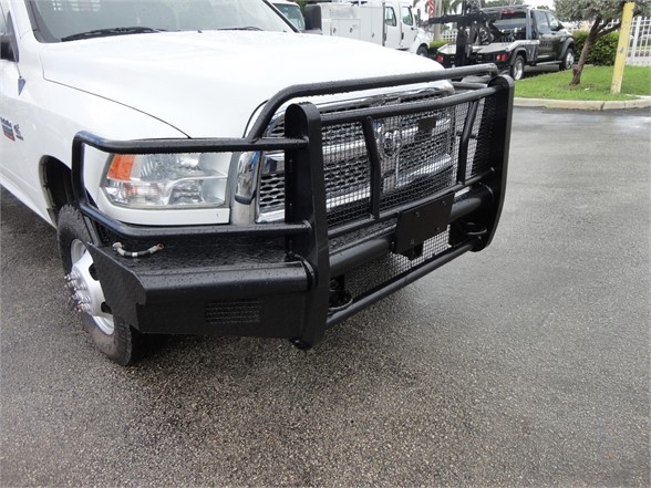 Front view of a white 2012 Ram 3500 SLT pickup with a heavy-duty black grille guard and bumper guard. Visible are the headlight, fender, and front left wheel.