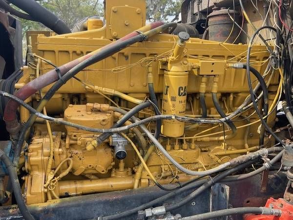 Peterbilt 359 diesel engine bay showing yellow engine with hoses, wiring, and filter canister.