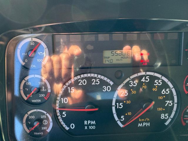 Dashboard of a Freightliner 114SD showing gauges including RPM, speed, and fuel/oil indicators.