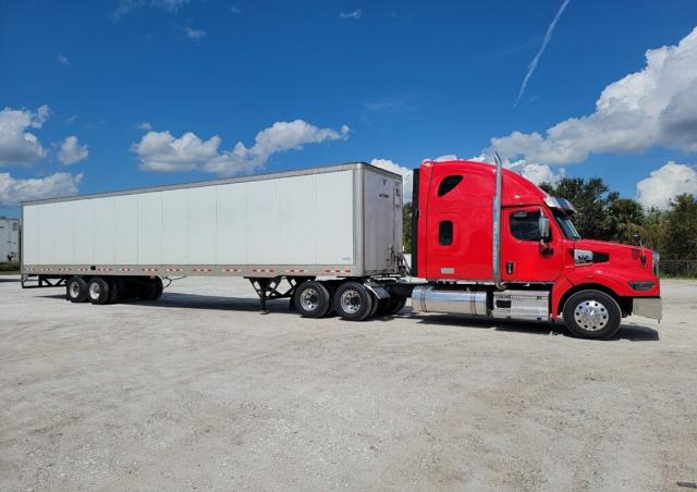 2023 Western Star 4900 truck with a red cab and white semi-trailer in a dirt lot.