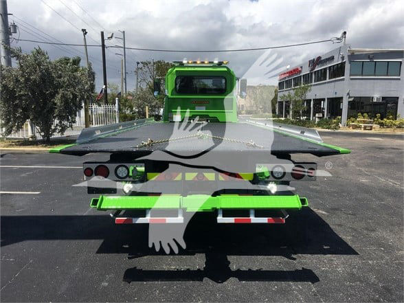 Truck bed of a 2022 Peterbilt 337 tow truck showing green paint, rear view with taillights and towing equipment.