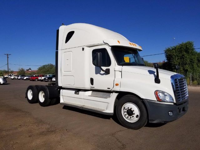 Truck cab of a white 2012 Freightliner Cascadia conventional sleeper shown from a side angle.