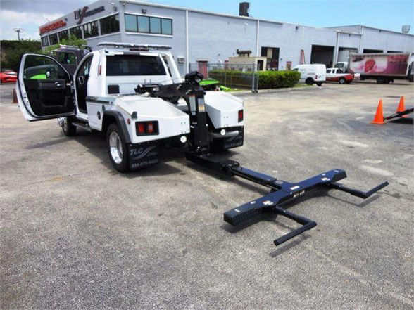 RAM 4500 tow truck with front doors open and a hydraulic tow arm extended in a dealership lot.
