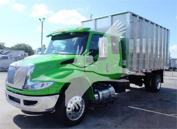 Green 2023 International MV dump truck in front view showing chrome front bumper and large aluminum dump body.