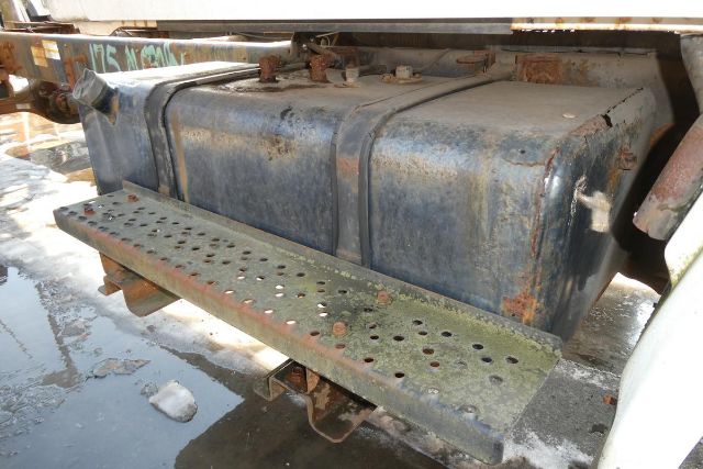 Fuel tank and rear step bumper on a Hino 145 cab chassis showing a weathered metal fuel tank and perforated step with rust patches.