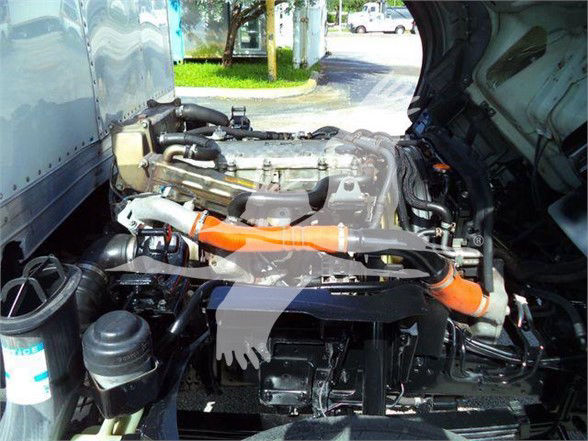 Isuzu NRR engine bay showing compact diesel engine with orange coolant hose and various black plastic and metal components