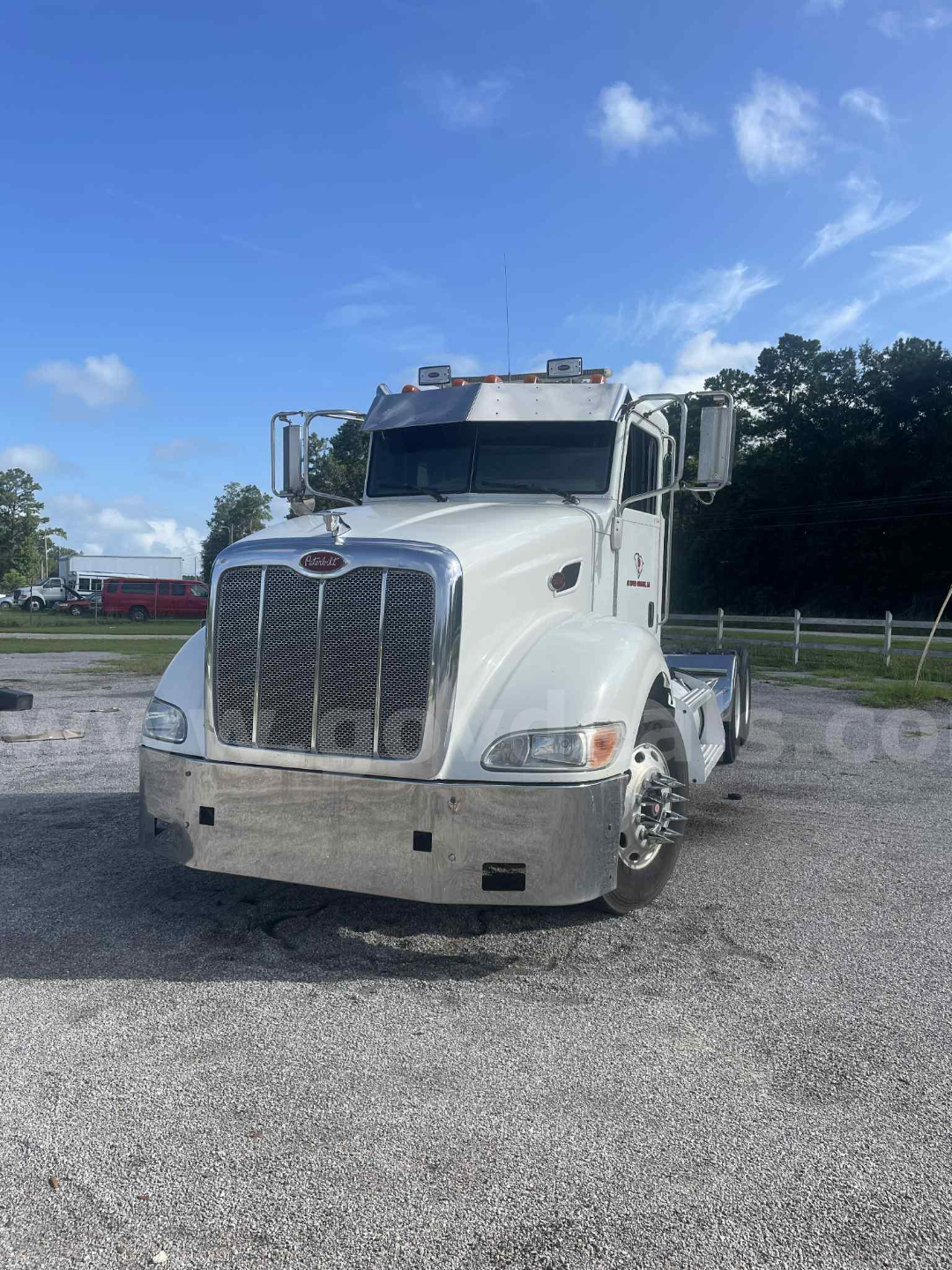 Peterbilt 386 cab and chassis front view showing large chrome grille, white paint, emblem, dual mirrors, and chrome bumper.