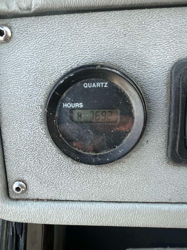 Quartz hour meter showing HOURS and 7692 on the gauge panel in a textured dashboard area.