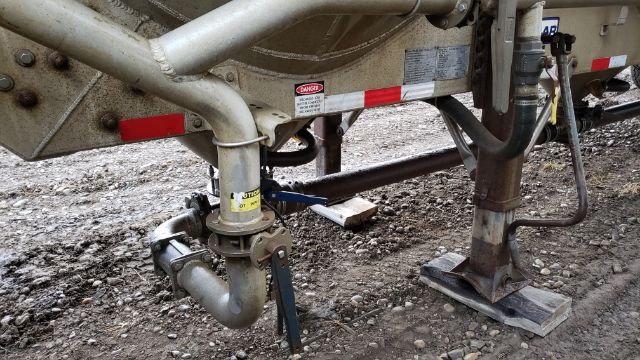 Trailer hitch area showing coupling and plumbing on underside of 2012 Polar Pneumatic 38 M3 trailer. Includes hitch with safety chains, piping, and support legs.