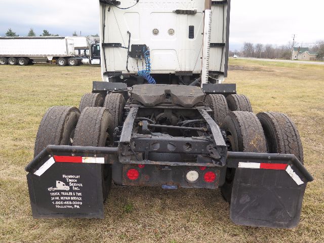 Rear view of a 2010 International PROSTAR truck chassis showing dual rear axles and mud flaps. Visible text on left mud flap reads 'Houlbolt Truck Service Inc', contact lines. The hitch and taillights are visible with some dirt.