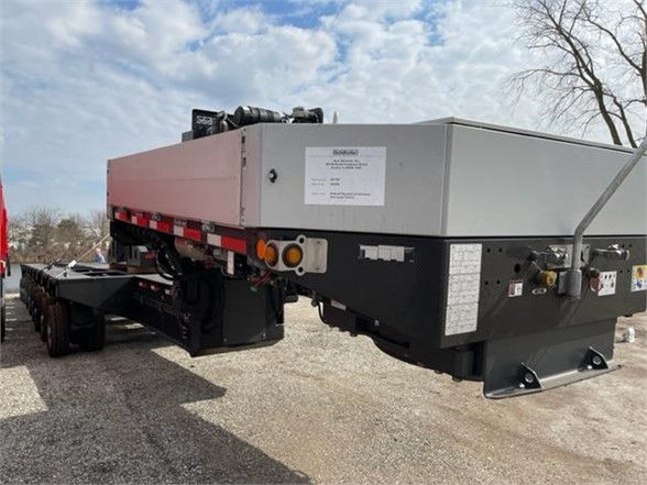 Truck trailer deck with label and warning stickers showing a raised grey deck and black undercarriage, side markings, and a white label on the side.