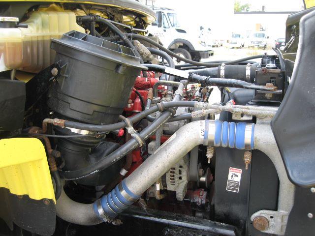 Freightliner M2106 engine bay showing coolant reservoir, hoses, and engine components.