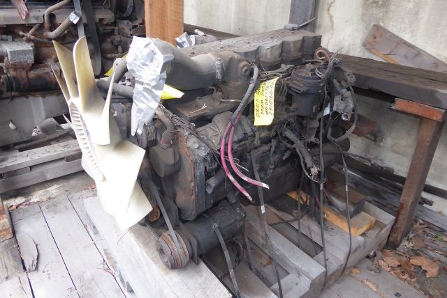 Engine block with hoses and wiring harness, front view, fan blades and red and pink electrical cables visible.