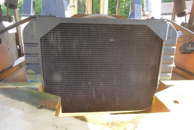 Caterpillar V225 truck equipment radiator cooling core in front view with surrounding yellow machinery.