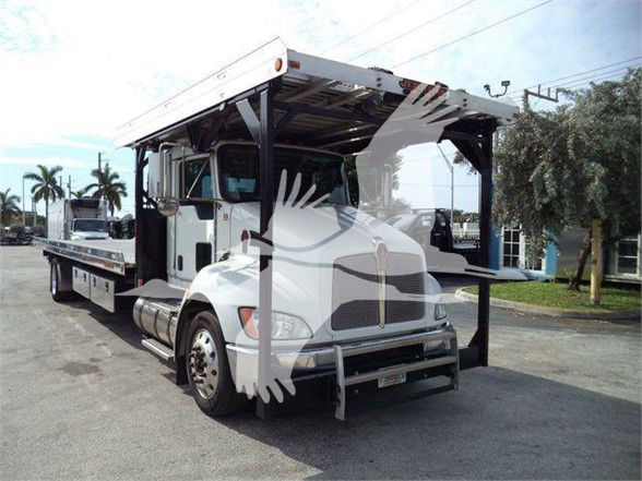 Tow truck showing a 2019 Kenworth T370 with a flatbed carrier and open cab, front view at an outdoor lot.