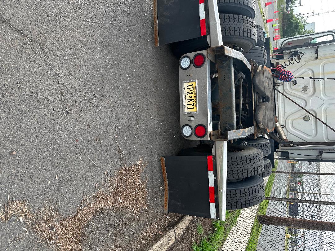 Rear view of a 2011 Freightliner Cascadia tractor-trailer with dual rear axles, license plate, and spare wheel visible.