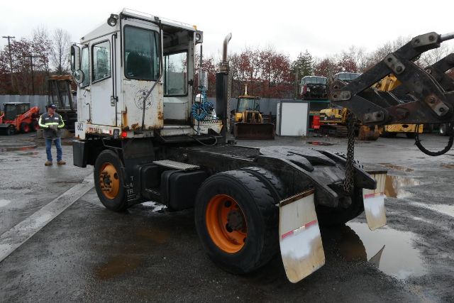 TJ5000 yard truck with orange rims and white cab, front view showing crane attachment and muddy ground.
