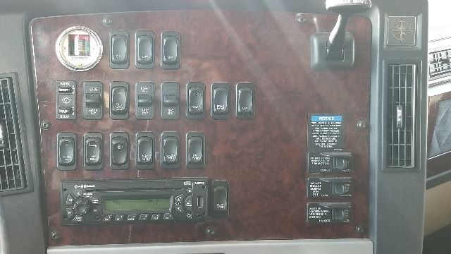 Dashboard panel of a Freightliner Coronado 132 showing numerous switches, gauges, and a radio unit.