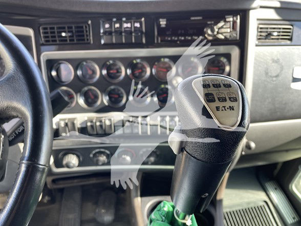 Kenworth T800 interior with floor shifter and dashboard gauges, showing steering wheel and gear selector with Eaton badge.