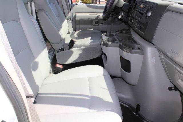 Ford E-450 interior front cabin with light gray seats and center console, steering wheel, dashboard, and cup holders visible.