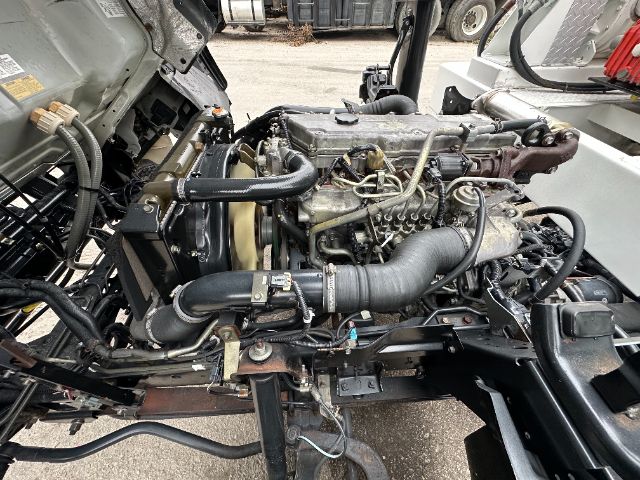 GMC W5500 engine bay with exposed engine and hoses; various labels and components visible in the bay.