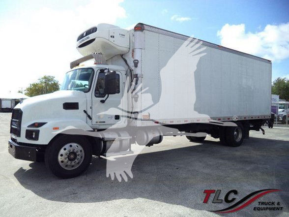 Truck with a refrigerated trailer and a mounted refrigeration unit on the cab, white color, CDL truck in a yard.
