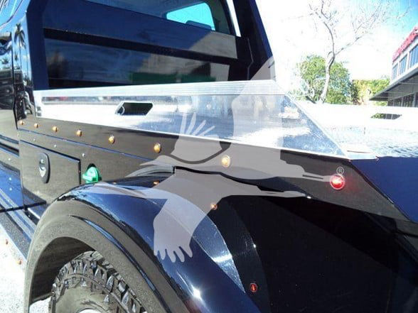 Truck fender and door area of a 2023 International CV heavy haul truck showing decorative side panel and chrome trim with rivets.